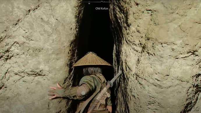 Naoe stands in front of a giant rift in a rock wall that leads to the Old Kofun in Assassin’s Creed Shadows.