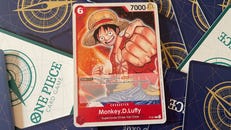 Monkey D. Luffy's character card in the One Piece Card Game arranged on a pile of facedown cards showing their backs.
