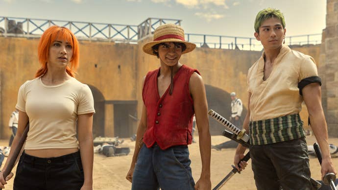 A still from Netflix’s One Piece showing Nami, Luffy, and Zoro all stood in a courtyard, all looking at something offscreen.