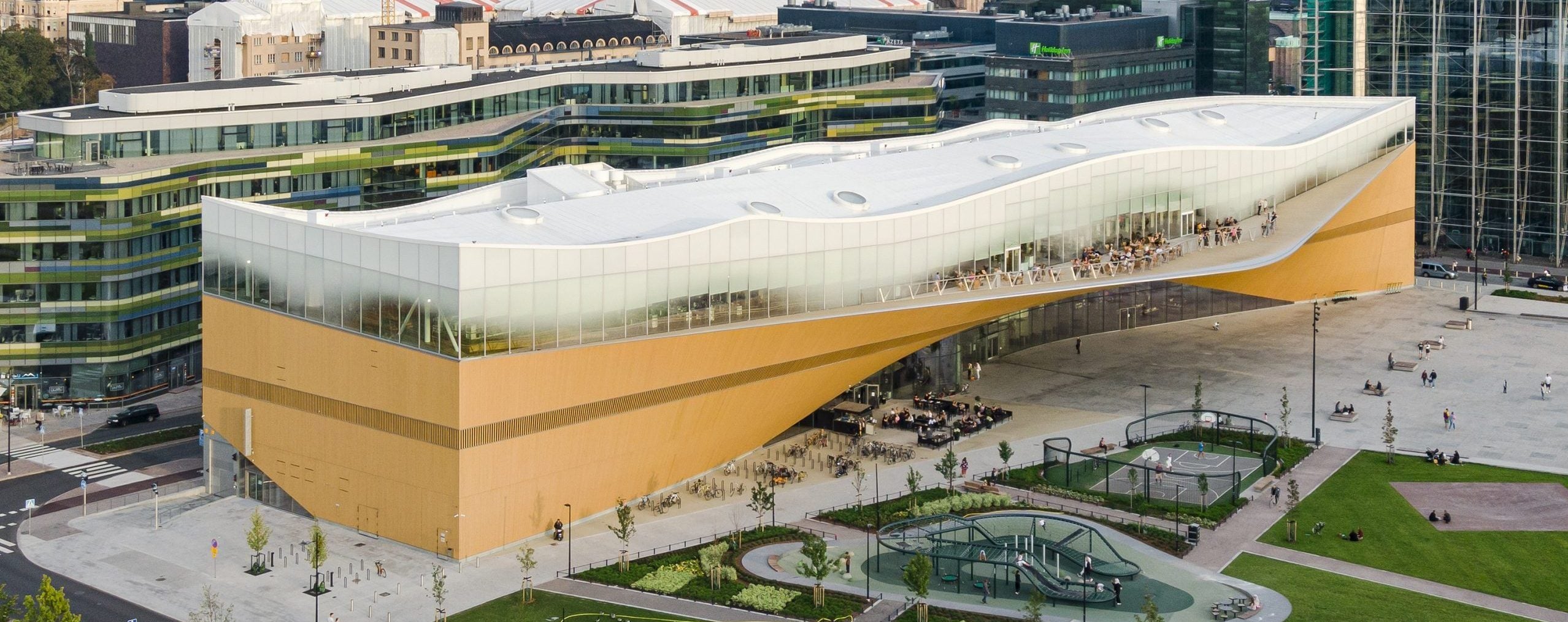 An aerial render of the Oodi Library in Helsinki, Finland. A rectangle with a wave on top made of glass, it looks almost like a 3D render in person, too.