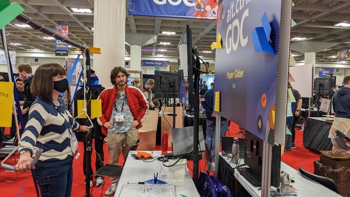 Katharine holds two levers attached to weights to control a tiny paper aeroplane at GDC