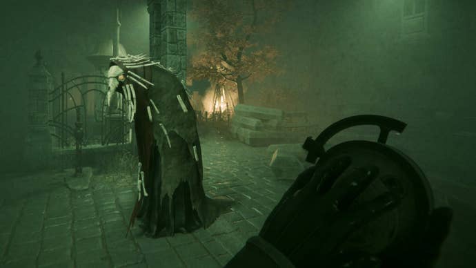 A Pathologic 3 screenshot showing the protagonist holding a strange watch-like device while observing an eerie masked creature prowling a foggy cobbled street.