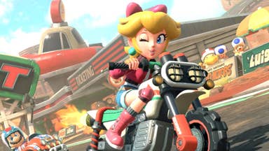 Princess Peach in Mario Kart World riding a motorbike and winking at the camera.