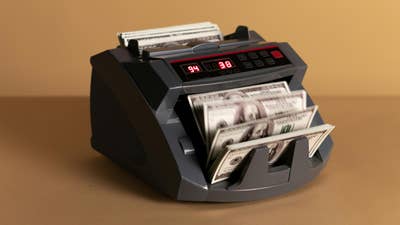 Picture of a banknote counter shuffling through US $100 bills