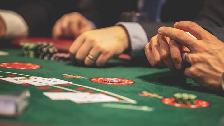 Close-up picture of a blackjack table with cards in play, several players' hands, and stacks of casino chips visible