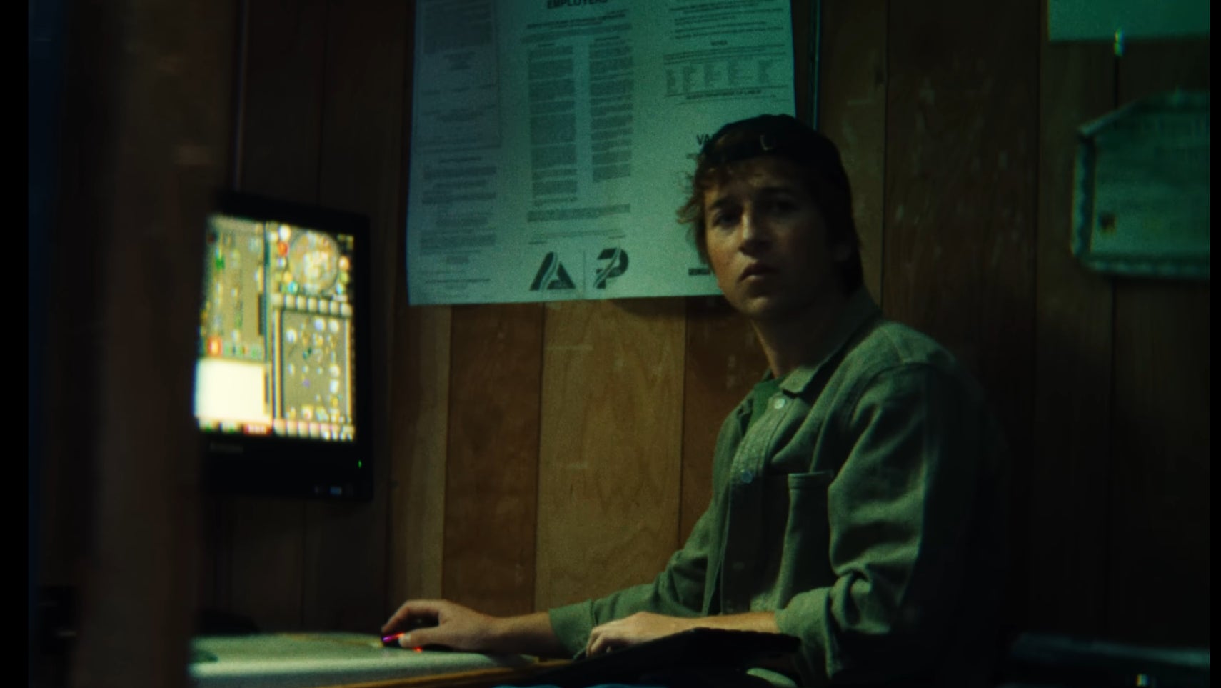 Screenshot from Phoebe Bridger's Lost Boys music video, where a man is seen playing Old School RuneScape at work.