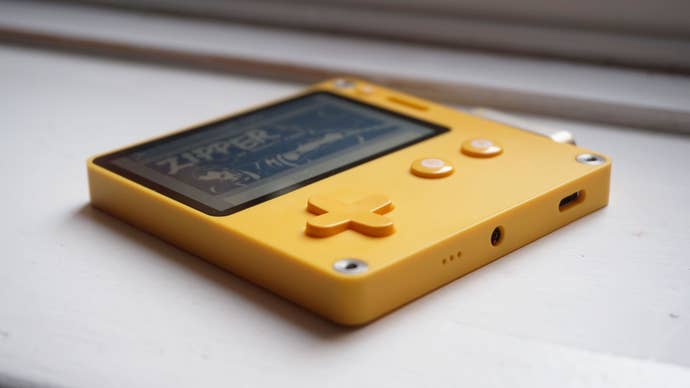 The Playdate lying on a white window sill, showing the bottom side of the console