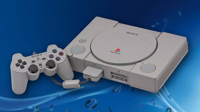 An original PlayStation in front of a blue, PlayStation-themed background.