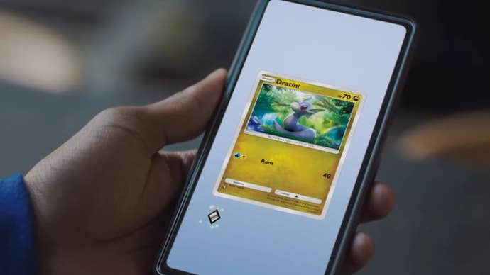 A person holding their phone playing Pokemon TCG Pocket, a Dratini card can be seen on screen.