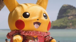 Pikachu mascot on a Hawaiian beach wearing a floral print red shirt and a lei