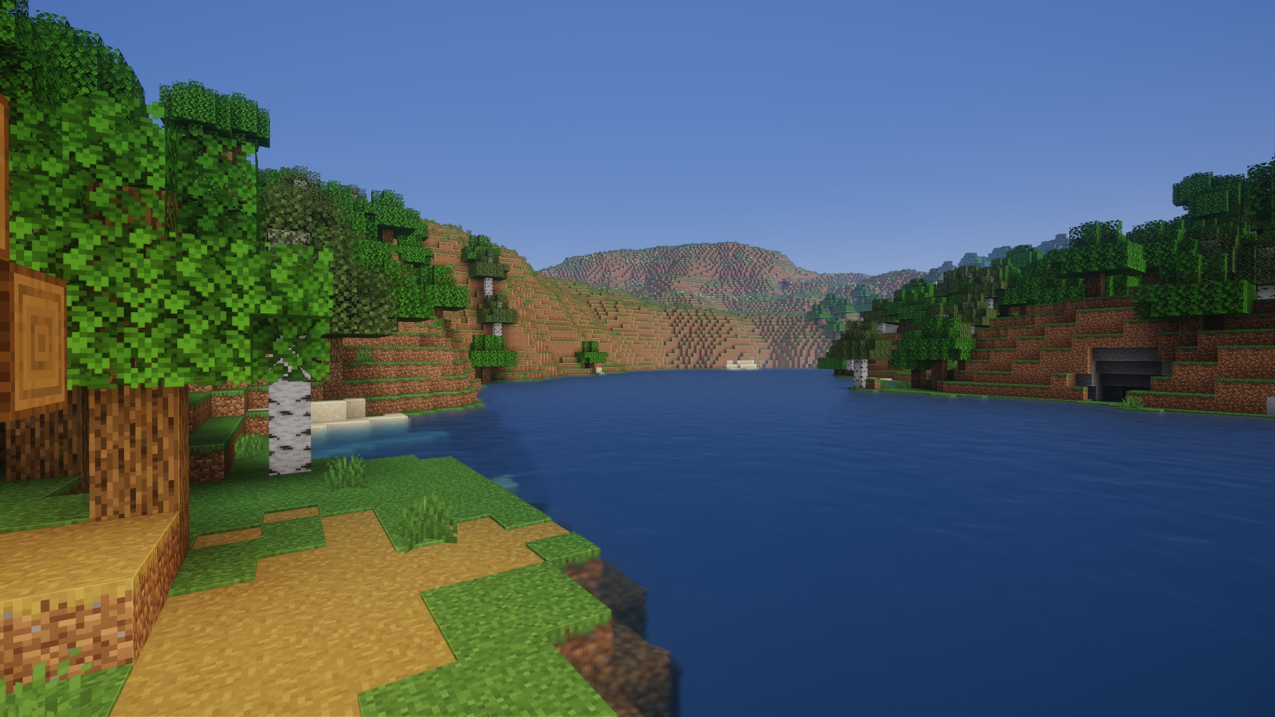 A screenshot of a river in Minecraft, with some trees on either side of the bank and a hill in the distance, taken using Potato shaders.