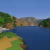 A screenshot of a river in Minecraft, with some trees on either side of the bank and a hill in the distance, taken using Potato shaders.
