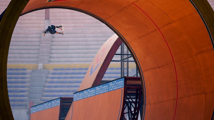 A screenshot from Tony Hawk's Pro Skater 1 + 2 showing a skater performing an ollie high above a half-pipe, as glimpsed through the opening of a full-pipe in the foreground.