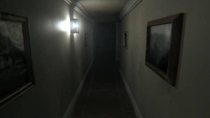An image of the hallway from P.T., a narrow plain white hallway with one harsh light on the wall in the middle distance that doesn't do much to light up the area. The hallway is quickly enveloped by darkness in the distance