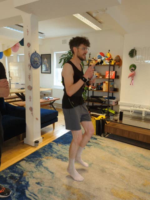 A gif of Bertie running on the spot in a vest and shorts and socks. He’s got the Quell gaming fitness gear on - a belt and some controllers tethered to him with resistance bands.