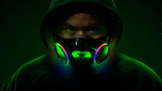 A man in a hood wearing Razer's Project Hazel face mask, and his face is illuminated by its interior RGB lighting