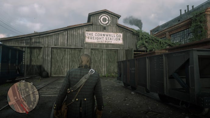 Arthur Morgan approaching the Cornwall Freight Station building in Red Dead Redemption 2.