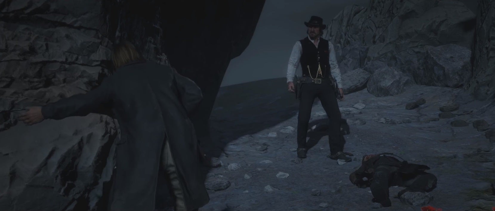 Two Red Dead Redemption 2 characters stand in a darkly-lit, rocky region during the game's ending. - 4