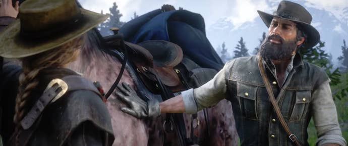 A Red Dead Redemption 2 character standing by a horse and patting it.