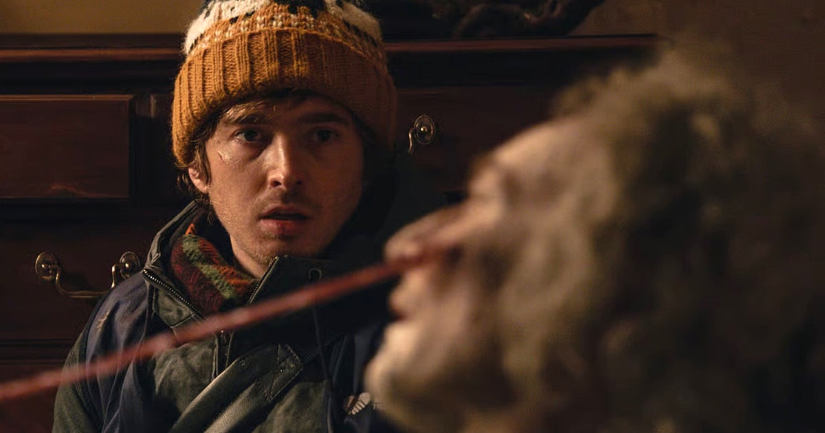 Resident Evil movie still showing bobble-hatted protagonist Bryan looking on as a tentacle emerges from a zombie's face.