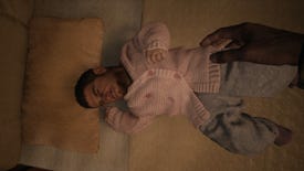 Resident Evil Village mod - A baby laying in a crib wearing a pink sweater has the face of adult Chris Redfield.