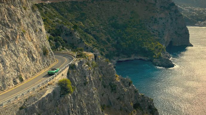 A car travels down a long, beautiful road sat snugly between a cliff and the ocean in 007: Road to a Million.