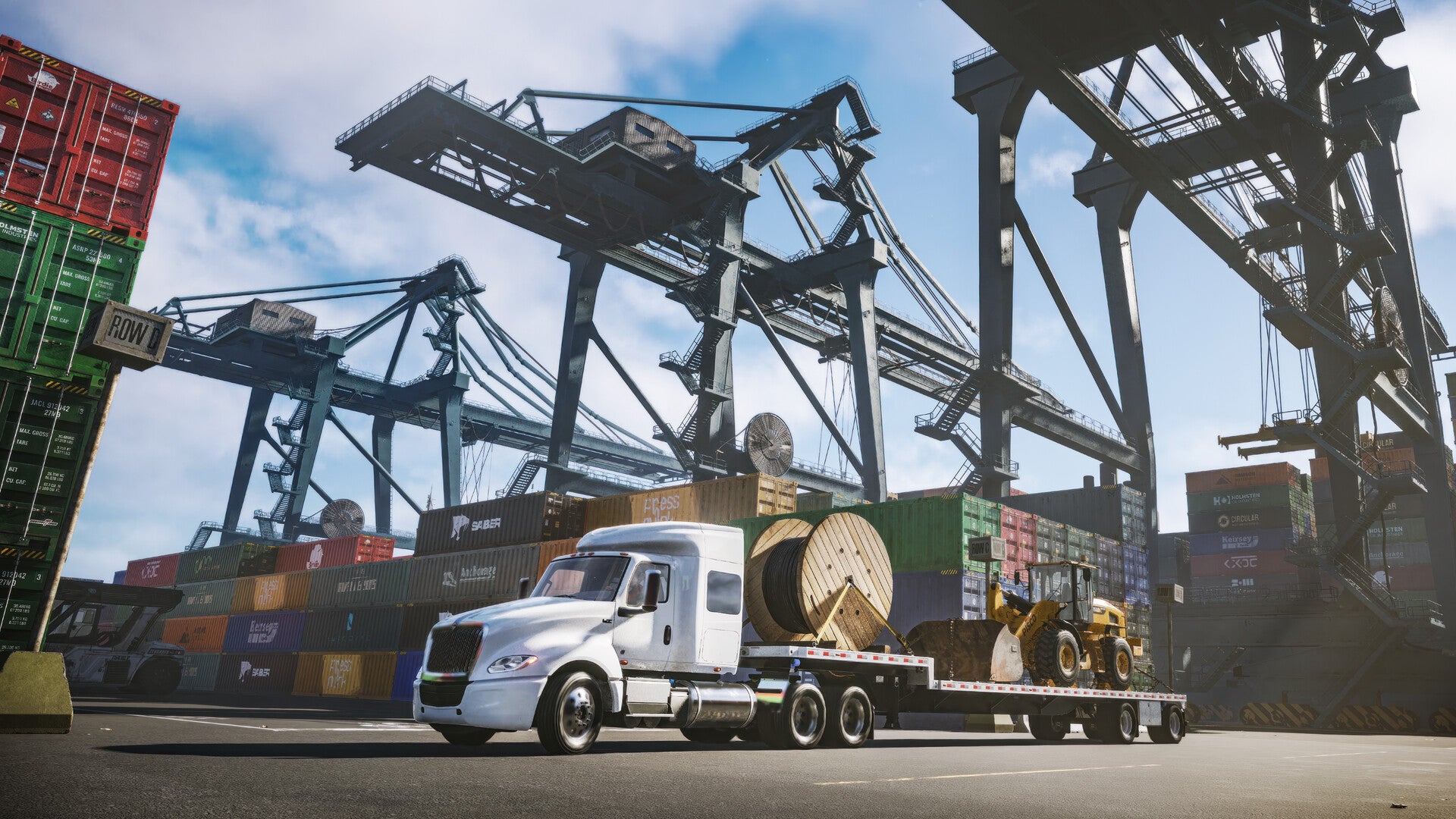 A big white truck with a bunch of construction stuff on its flatbed, parked under some shipping cranes. From Road King.