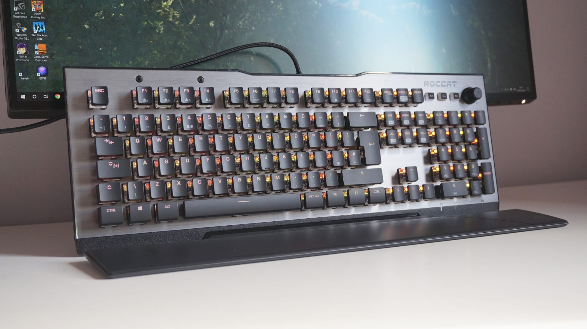 The Roccat Vulcan 120 gaming keyboard, propped up in front of a desktop monitor.