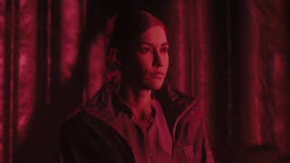 Kiran Estevez stands bathed in a red light in Alan Wake 2's The Lake House DLC.