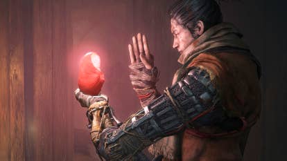 A samurai, side-on, holding what looks to be a glowing baby doll in their hand, and praying to it. They have a mechanical arm.