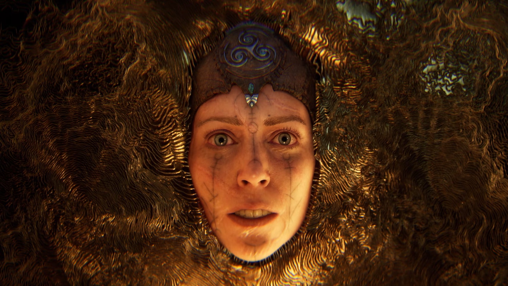Senua screenshot showing its titular protagonist's face staring at the camera as it slowly sinks into golden liquid.