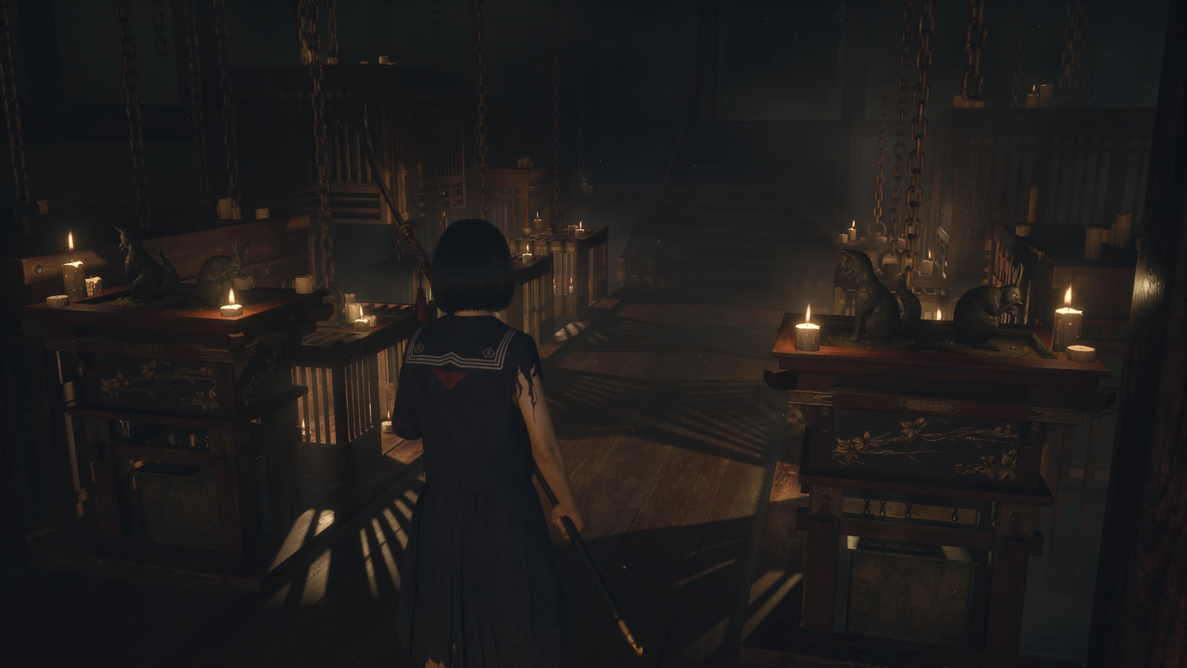 Hinako stands in a wooden room. Lit by candlelight, you can make out several wooden cages around the room. In front of her are four bronze statues.