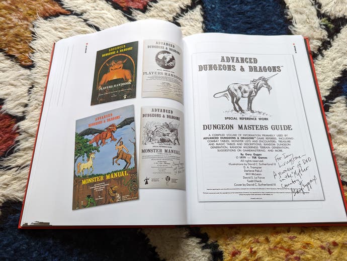 A photo of the Dice Men Games Workshop book, showing two pages of original Dungeons & Dragons paraphernalia, including a copy of Advanced D&D signed by co-creator Gary Gygax.