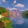 A screenshot of a river in Minecraft, with some trees on either side of the bank and a hill in the distance, taken using Sildur's shaders.