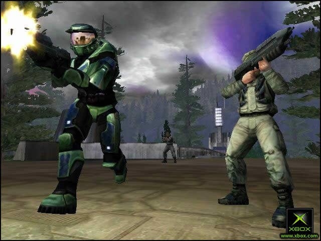 Original Halo screenshot showing Master Chief running toward the camera and firing off screen. Another marine holds a rifle aiming off to the opposite side of the screen.