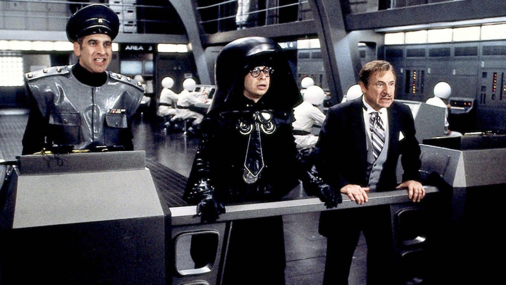 Still from Spaceballs showing Rick Moranis in a outfit parodying Darth Vader, he's wearing a similar helmet but it is massive, dwarfing his head. - 1