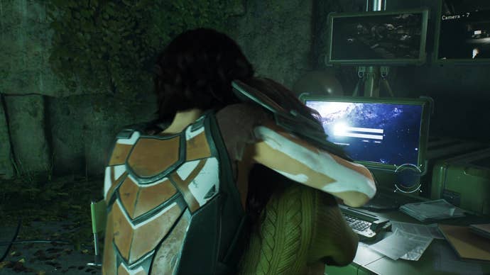 A female hunter, Vika, grabs MJ around the neck from behind while the latter stands at a computer desk inside the Hunter base.