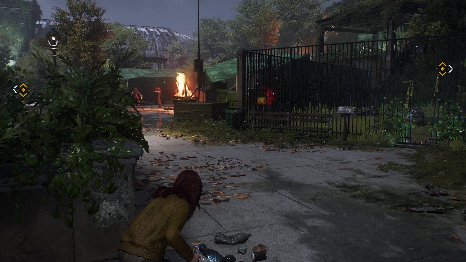 Mary Jane crouches at the foot of the zoo entrance stairs, with an enclosure ahead of her and a lean-to and bonfire over to the left. - 3