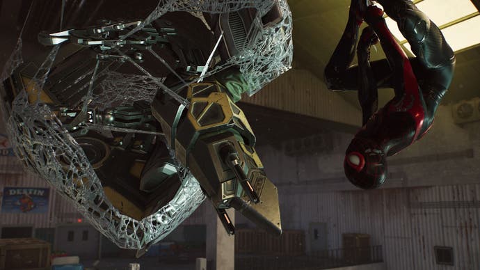spider-man 2 miles is hanging upside down next to the webbed drone in the fish market.