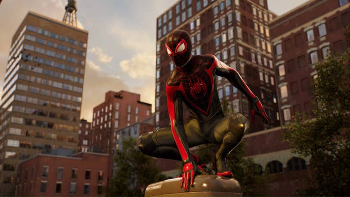 spider-man 2 miles morales crouching on a post in his black and red suit.