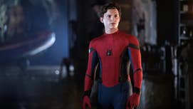 Tom Holland as Spider-Man, stood in a dimly lit area wearing his Spider-suit, mask off, looking at something offscreen.
