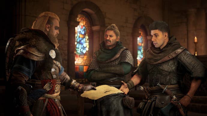 Screenshot from Assassin’s Creed Valhalla showing male Viking Eivor chatting with two other male characters in a large room with ornate stained glass windows