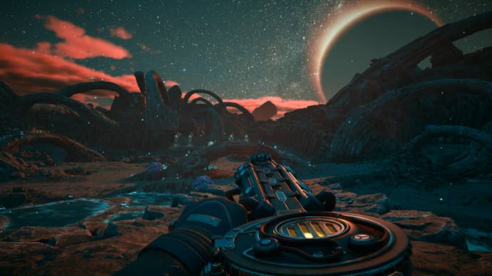 A first-person view of a character carrying a large, circular-drummed sci-fi gun on a sci-fi planet. Obligatory low-hanging moon can be seen on the horizon.