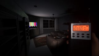 A screenshot of Phasmophobia showing a dimly lit living room viewed in first-person at night. Its furnishing are cast in shadow and the only source of light is a TV screen showing a test signal near a window to the rear of the room. The unseen investigator surveying the scene holds up a small handheld electronic device labelled 'spirit box' with two rows of buttons beneath an orange digital display.