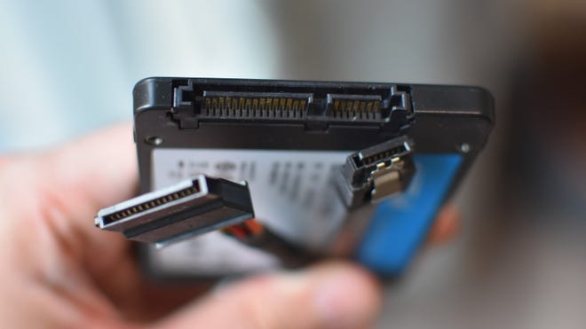 A 2.5in SSD’s connection ports, held next to the corresponding power and data cables.