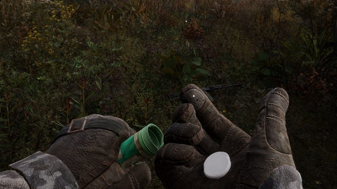 A close-up of the player's hands in Stalker 2 as he pours the Hercules pill from the tube into his hand.