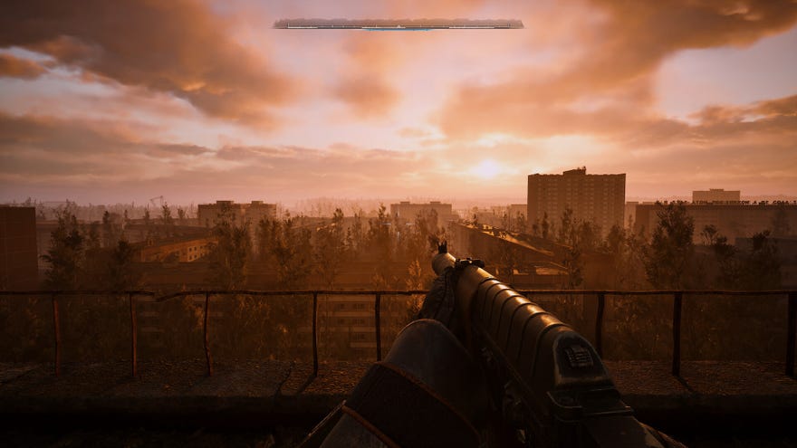 The player in Stalker 2 stands atop a roof in a settlement and looks out towards the sunset while holding their rifle.