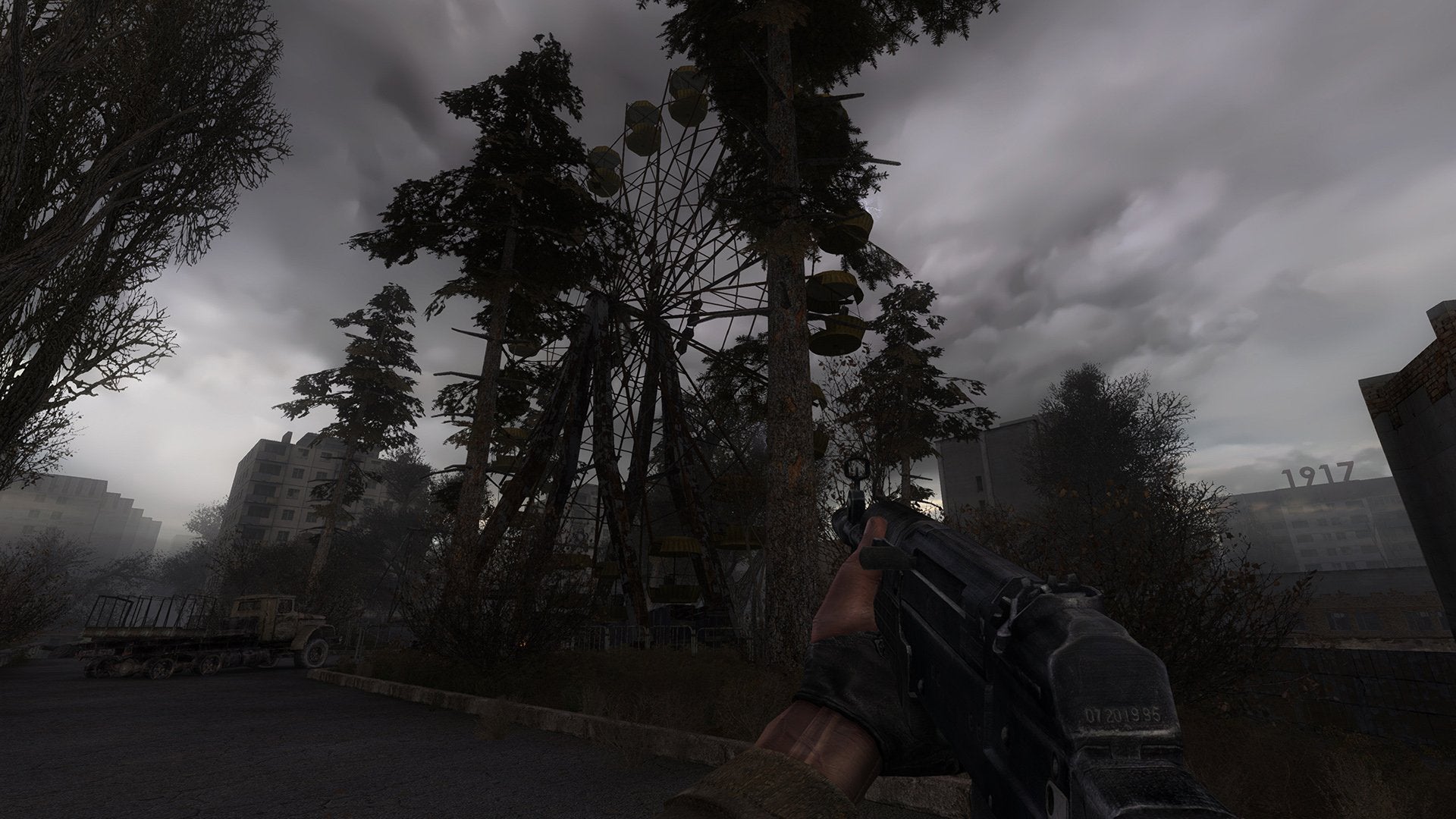 A first-person perspective of someone holding a gun in a dilapidated area, trees and a ferris wheel in view in a screenshot from the Stalker series. - 1