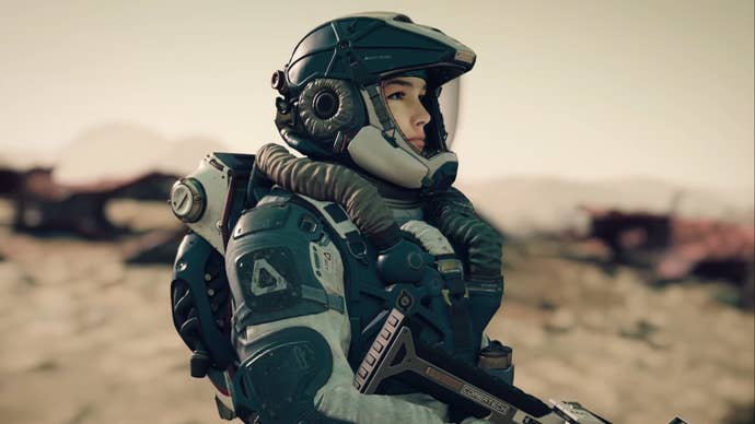 A Starfield character is wearing exploration armor and a helmet while standing on a desolate planet, they’re holding a weapon and looking out ahead of them.