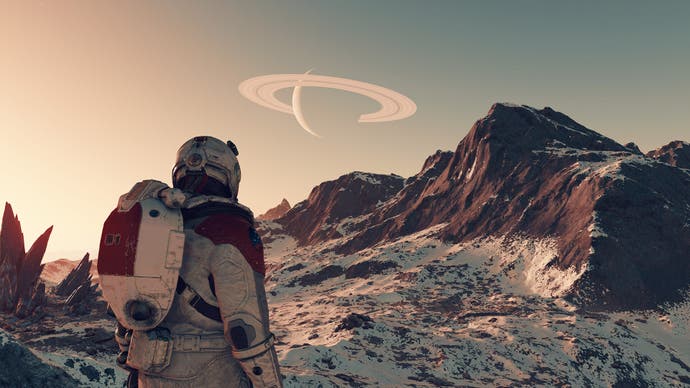 A Starfield screenshot showing an astronaut standing in a barren, mountainous environment gazing up at a ringed planet visible in the hazy sky.